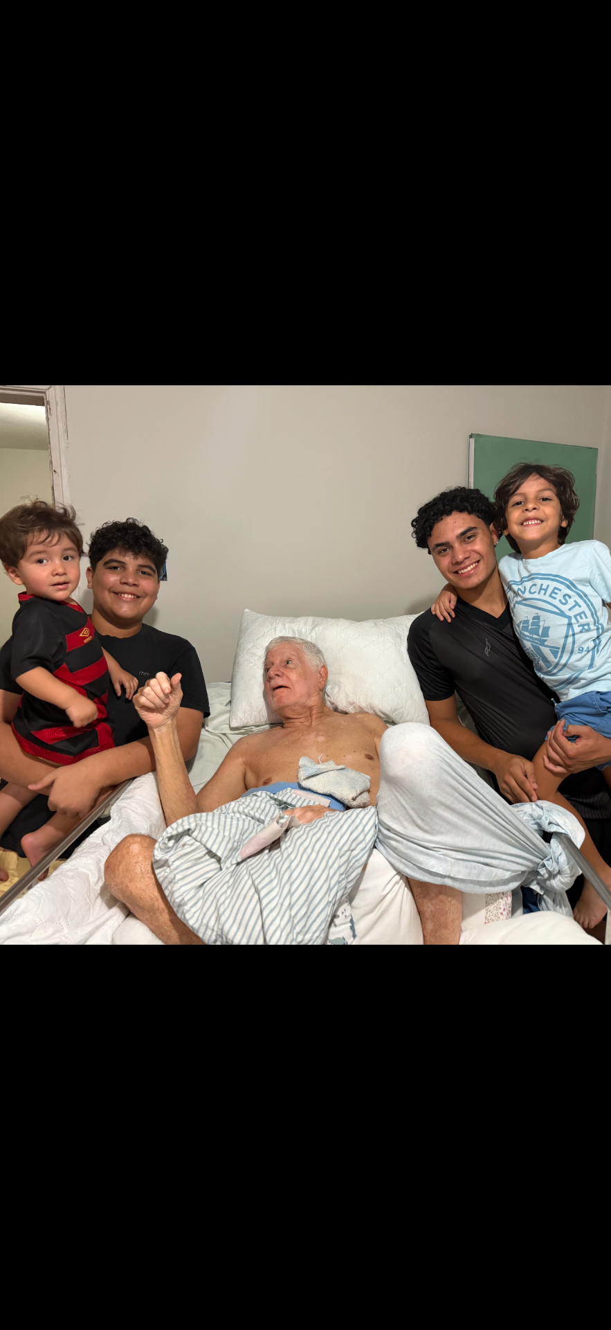 Pai do fundador do VóCuida acamado, cercado pelos netos sorrindo